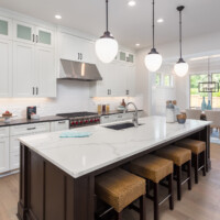 kitchen in newly constructed luxury home beautiful kitchen in new luxury home with island, pendant lights, and hardwood floors. includes view of dining room.